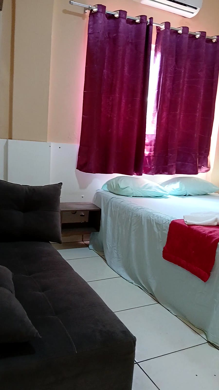Apartamento com cama de casal e enxoval branco e vermelho