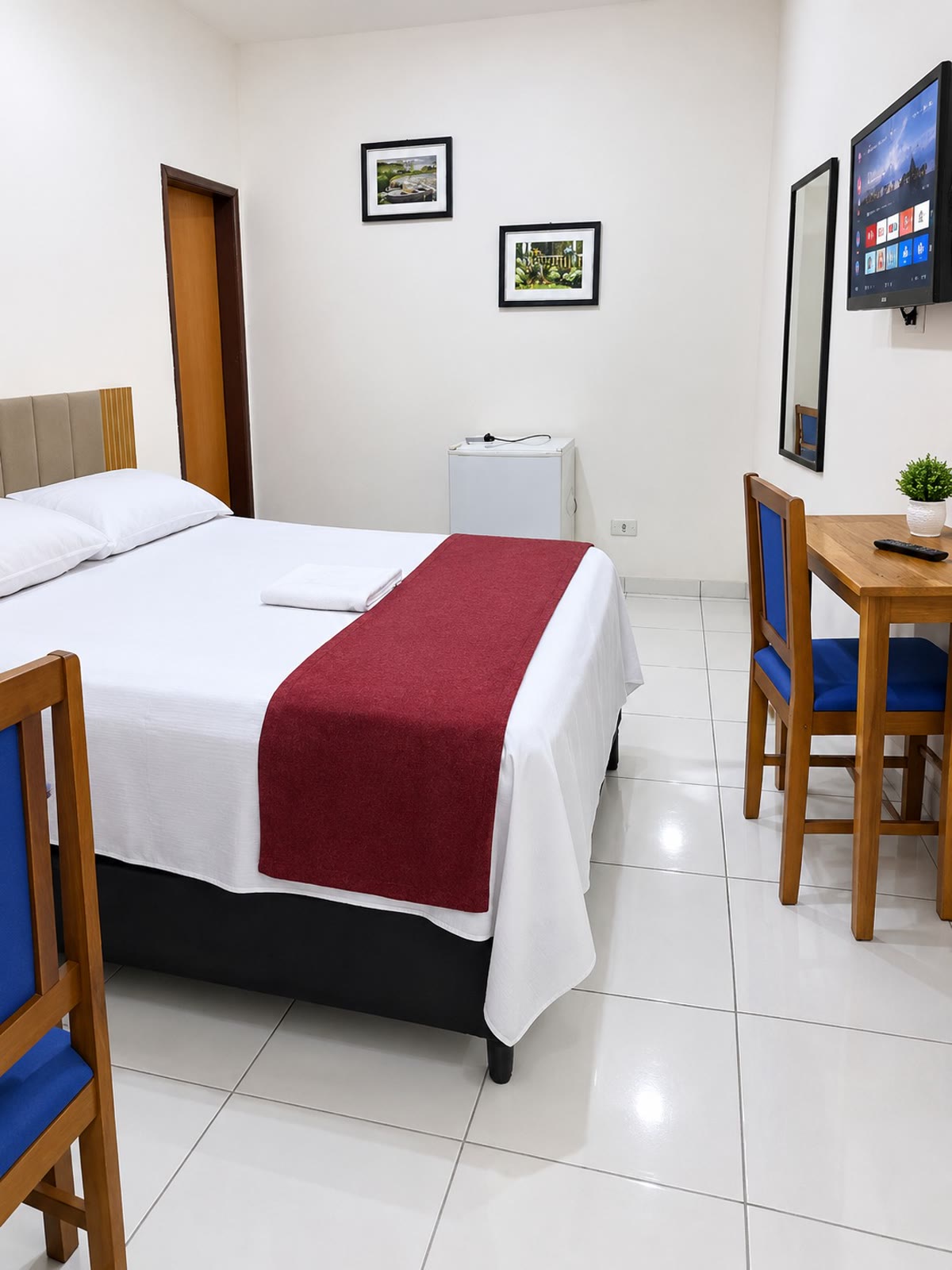 Apartamento com cama de casal, TV, frigobar e mesa com cadeiras